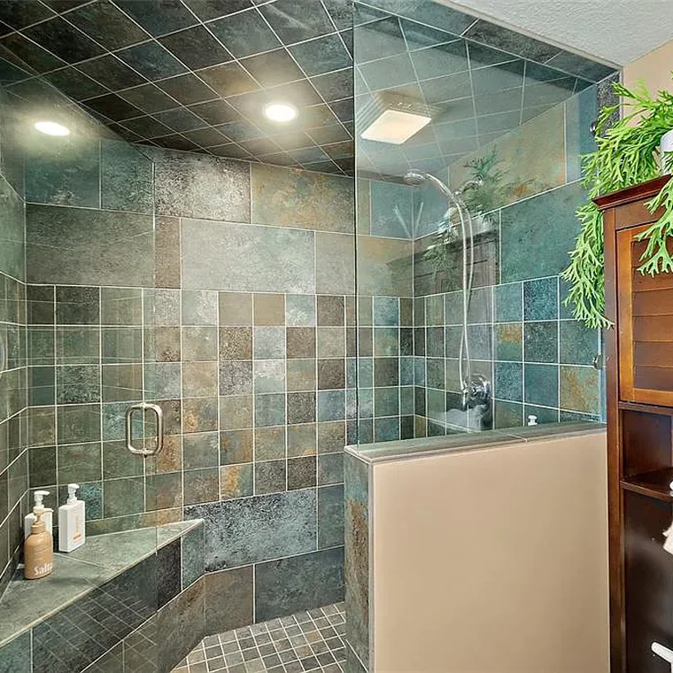 Walk-in slate tile shower with glass enclosure in the primary bathroom