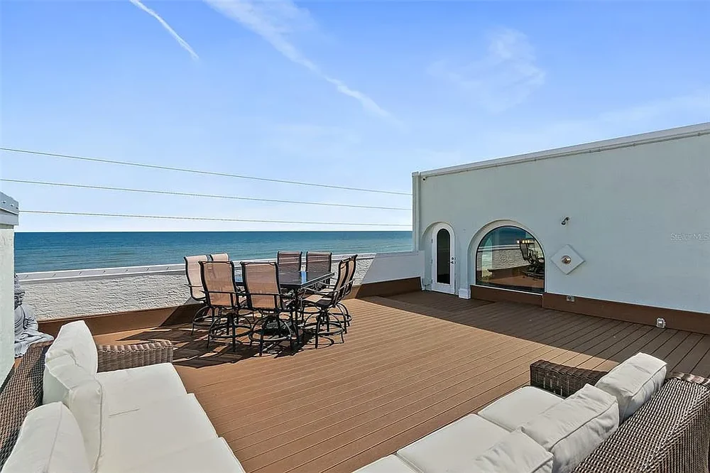 Private rooftop deck with lounge seating and outdoor dining set overlooking the Atlantic Ocean at 3390 Ocean Shore Blvd Unit 402