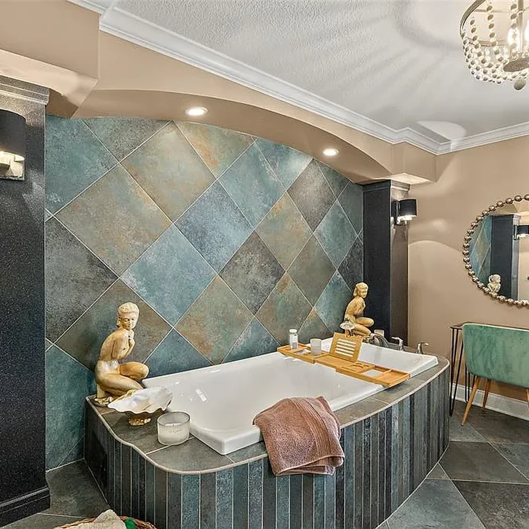 Spa-inspired primary bathroom with slate tile surround and deep soaking tub